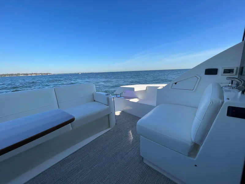 Slide: The Image of 2021 Tiara Yachts C49 Coupe deck with seating, overlooking calm ocean waters. - 9