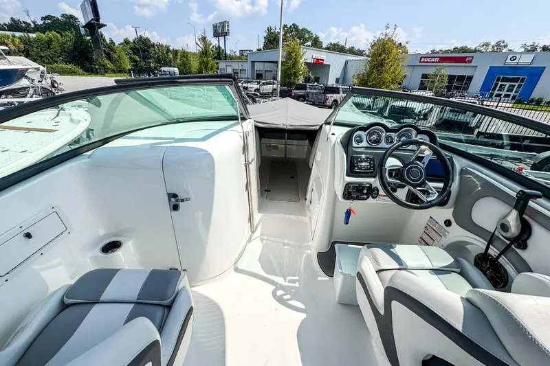 Slide: The Image of 2022 NauticStar 243 DC boat interior with steering wheel and seating, parked outdoors. - 10
