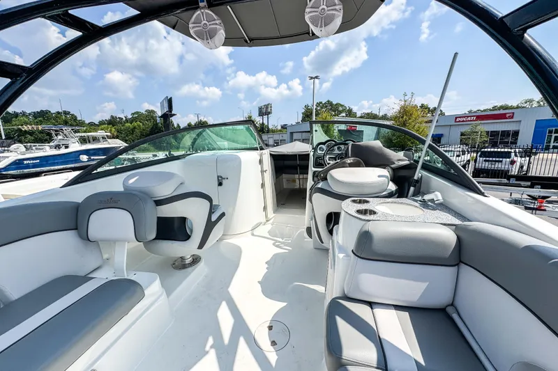 Slide: The Image of 2022 NauticStar 243 DC boat interior with seating and dashboard, under a sunny sky. - 4