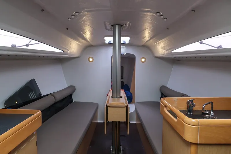 Slide: The Image of Interior of 2017 Jeanneau SunFast 3200 sailboat with modern seating and compact kitchen area. - 29