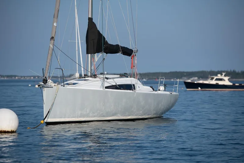 Slide: The Image of 2017 Jeanneau SunFast 3200 sailboat anchored on calm water, with distant boats. - 3