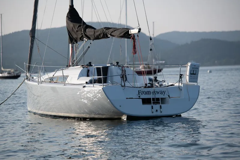 Slide: The Image of 2017 Jeanneau SunFast 3200 sailboat anchored on calm water with scenic mountain backdrop. - 4