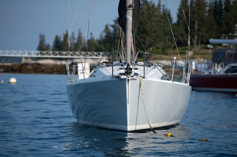 Slide: The Image of 2017 Jeanneau SunFast 3200 sailboat on calm water with forested shoreline background. - 5