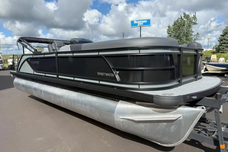 Slide: The Image of 2026 Godfrey SWEETWATER 2286 SFL pontoon boat on display under cloudy sky. - 2