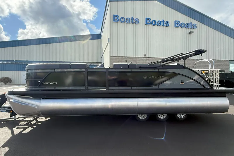 Slide: The Image of 2026 Godfrey SWEETWATER 2286 SFL pontoon boat outside dealership under cloudy sky. - 3