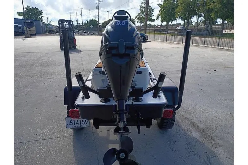 Slide: The Image of 2013 Pelican Ambush boat on trailer, parked at a marina with other boats. - 2