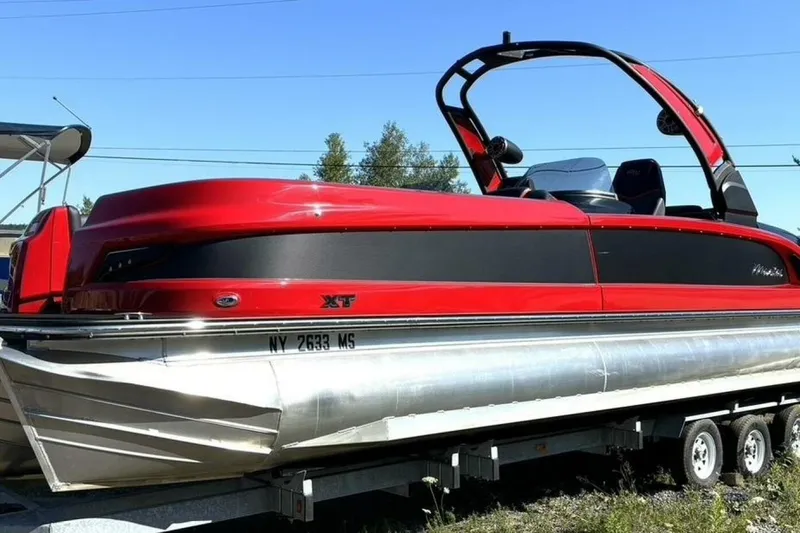 Slide: The Image of 2022 Manitou XT 27 SRW pontoon boat in vibrant red on a trailer. - 2