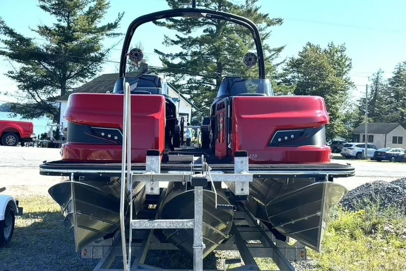 Slide: The Image of 2022 Manitou XT 27 SRW pontoon boat with red exterior, parked on a trailer. - 3