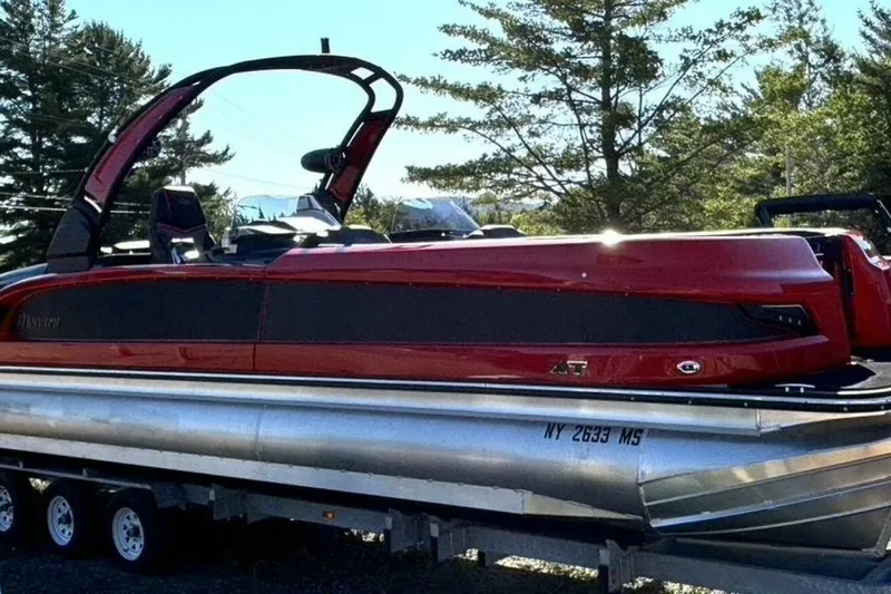 Slide: The Image of 2022 Manitou XT 27 SRW pontoon boat in vibrant red, parked on a trailer. - 4