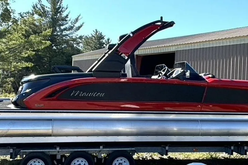 Slide: The Image of 2022 Manitou XT 27 SRW pontoon boat on trailer, red and black design, outdoors. - 5