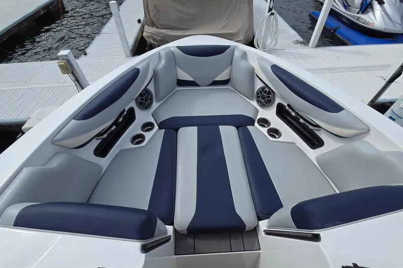 Slide: The Image of 2019 Axis T23 boat interior with blue and gray seating, cup holders, and speakers at a dock. - 12