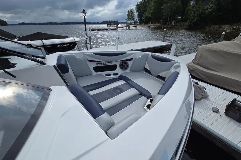 Slide: The Image of 2019 Axis T23 boat interior with cushioned seating, docked by a lake under cloudy skies. - 13