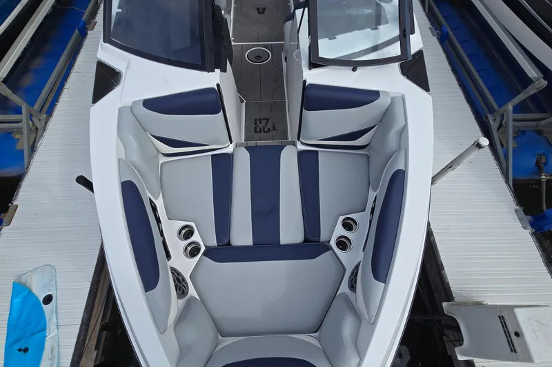 Slide: The Image of 2019 Axis T23 boat interior with blue and gray seating, docked at a marina. - 15