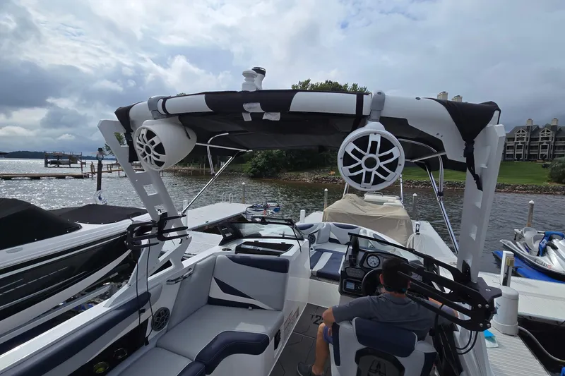 Slide: The Image of 2019 Axis T23 boat docked, featuring speakers and canopy, with scenic waterfront view. - 16