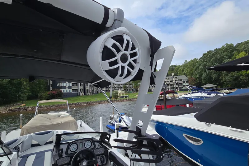 Slide: The Image of 2019 Axis T23 boat with speaker system, docked near waterfront homes and other boats. - 23