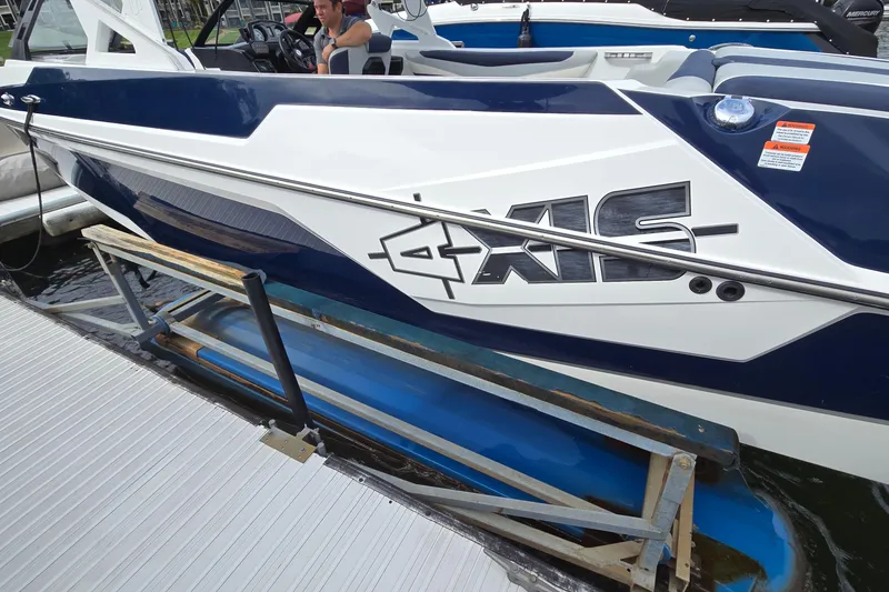 Slide: The Image of 2019 Axis T23 boat docked, featuring sleek blue and white design. - 3