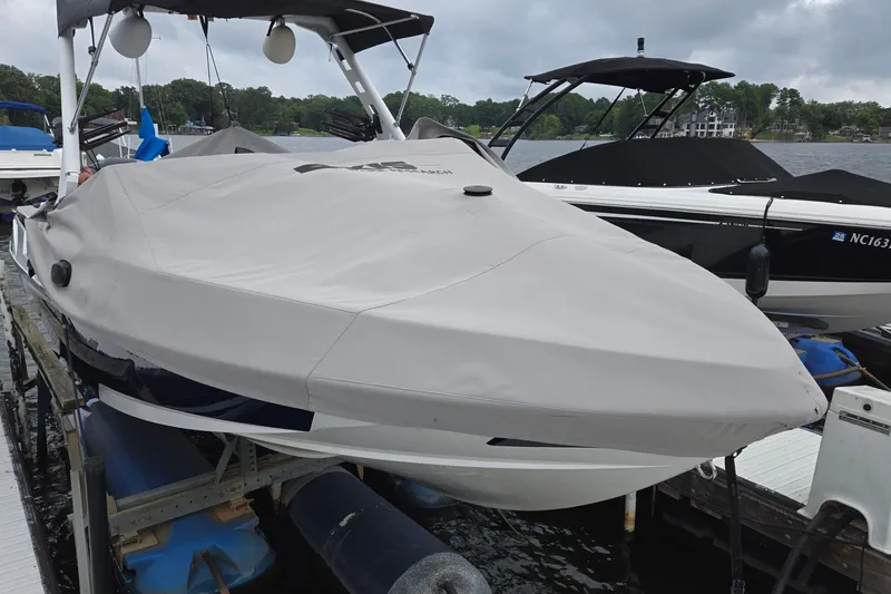 Slide: The Image of 2019 Axis T23 boat covered at dock, overcast sky, calm lake background. - 5