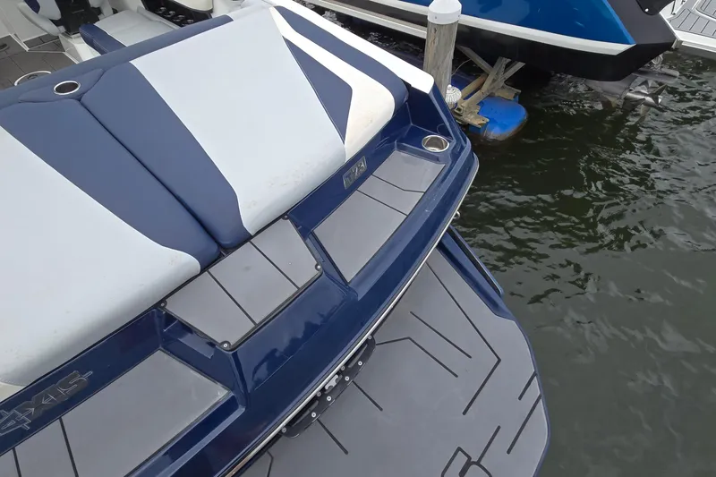 Slide: The Image of 2019 Axis T23 boat rear view with blue and white seating, docked on water. - 6