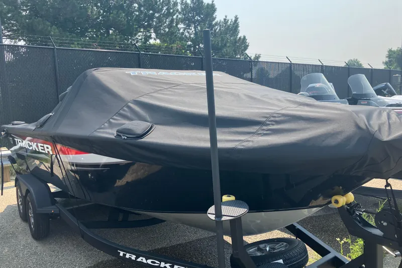 Slide: The Image of 2025 Tracker Targa V-19 Combo boat covered, parked on a trailer outdoors. - 9