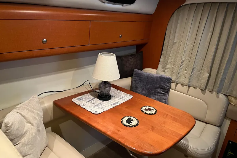 Slide: The Image of Cozy interior of 2005 Chaparral 270 Signature with wooden table, lamp, and cushioned seating. - 4