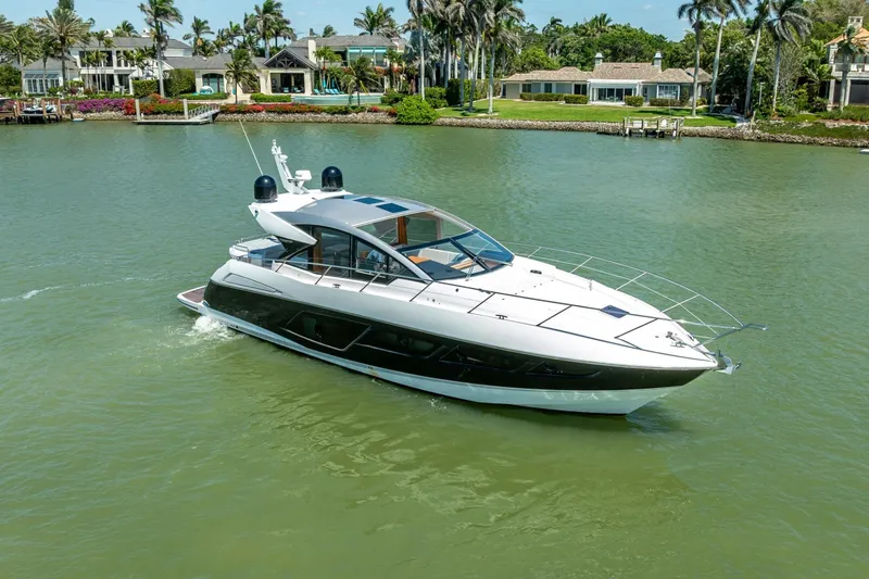 Slide: The Image of 2018 Sunseeker Predator 57 yacht cruising on a serene waterway with luxury homes in the background. - 16