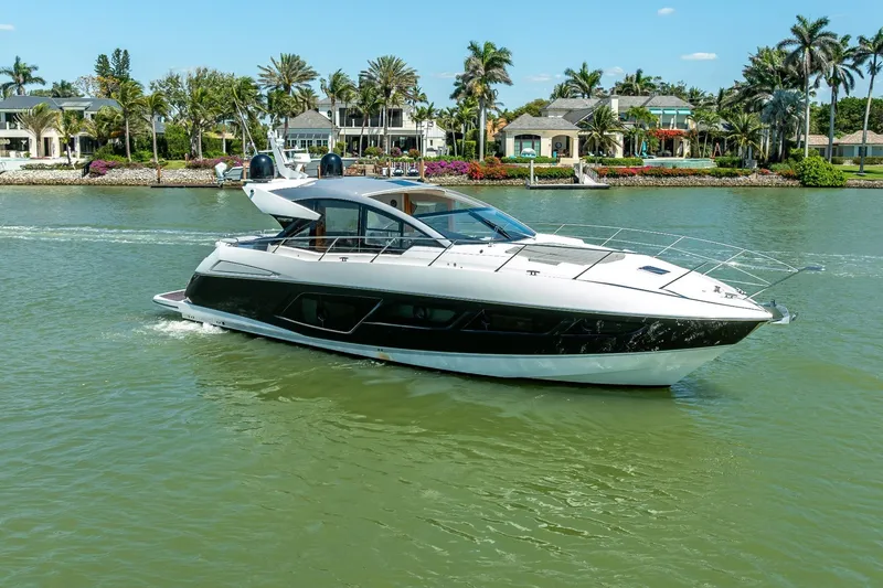 Slide: The Image of 2018 Sunseeker Predator 57 yacht cruising on a scenic waterway with luxury homes. - 21