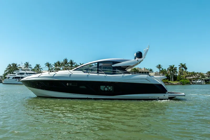 Slide: The Image of 2018 Sunseeker Predator 57 yacht cruising on a sunny day, surrounded by palm trees. - 14