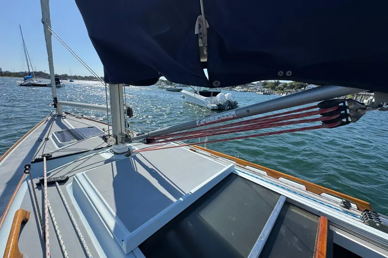 Slide: The Image of Sailboat deck view of 2000 Alerion Express 28 on water, featuring rigging and blue cover. - 6