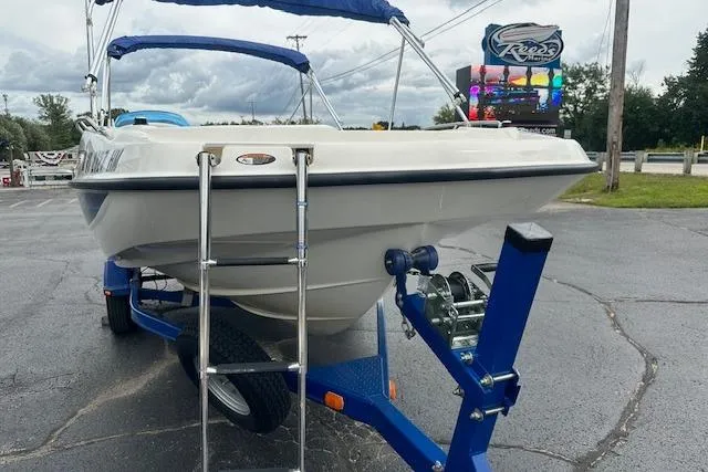 Slide: The Image of 2006 Bayliner 217 Deck Boat on trailer with ladder, parked outdoors. - 14