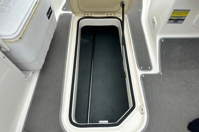 Slide: The Image of Open storage compartment on a 2006 Bayliner 217 Deck Boat, featuring carpeted flooring. - 15
