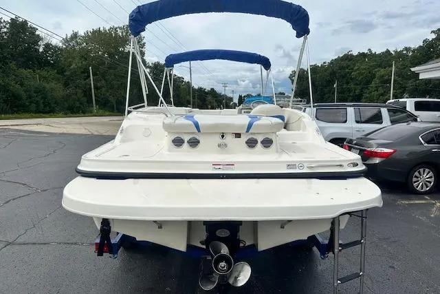 Slide: The Image of 2006 Bayliner 217 Deck Boat with blue canopy, parked on asphalt, rear view. - 3