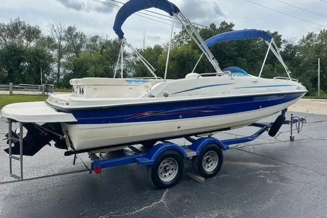 Slide: The Image of 2006 Bayliner 217 Deck Boat on trailer, blue and white design, parked outdoors. - 4