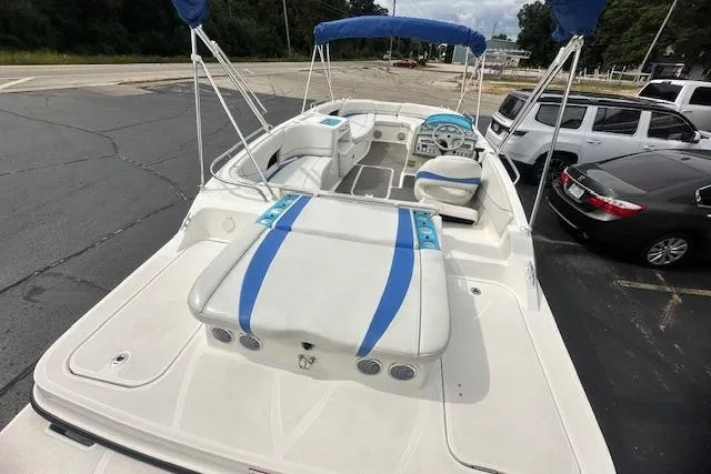 Slide: The Image of 2006 Bayliner 217 Deck Boat with blue accents, parked in a lot, featuring spacious seating. - 5