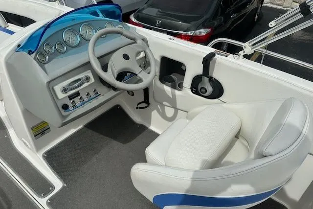 Slide: The Image of 2006 Bayliner 217 Deck Boat cockpit with steering wheel, gauges, and white seating. - 8