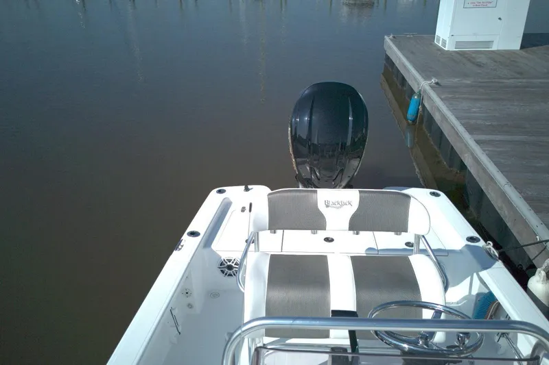 Slide: The Image of 2024 BlackJack 224 boat docked, featuring sleek seating and powerful outboard motor. - 3