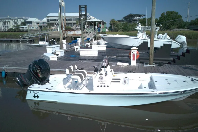 Slide: The Image of 2024 BlackJack 224 boat docked at a marina with dual outboard motors. - 4