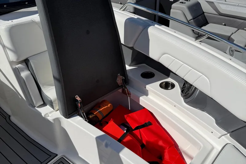 Slide: The Image of 2016 Chaparral 307 SSX boat storage compartment with safety equipment and cup holders. - 19