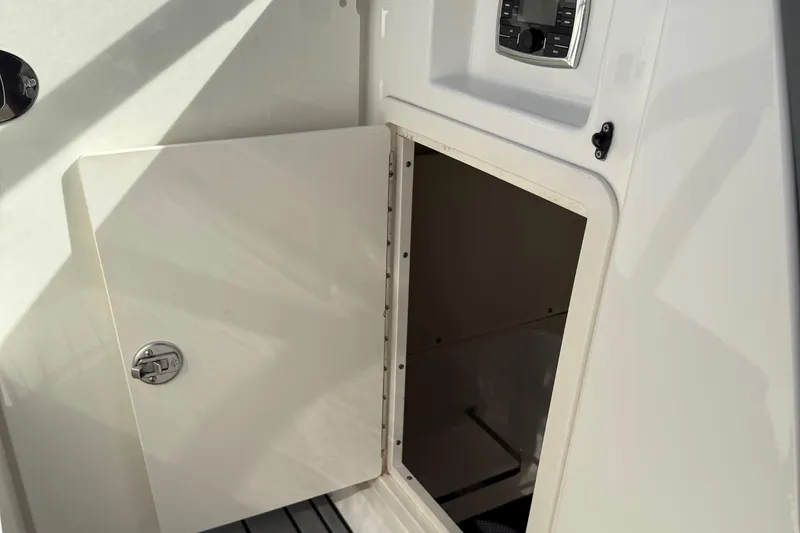 Slide: The Image of Open storage compartment on 2016 Chaparral 307 SSX boat, featuring a control panel. - 35