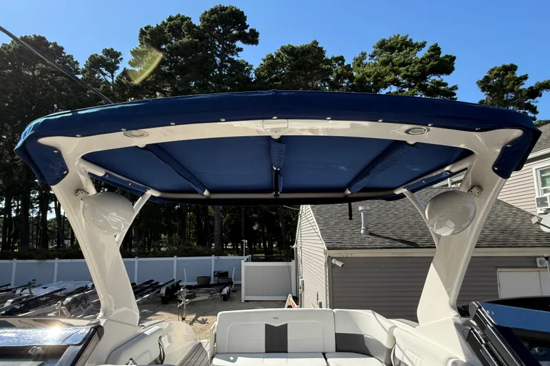 Slide: The Image of 2016 Chaparral 307 SSX boat with blue canopy and white seating, parked outdoors. - 53
