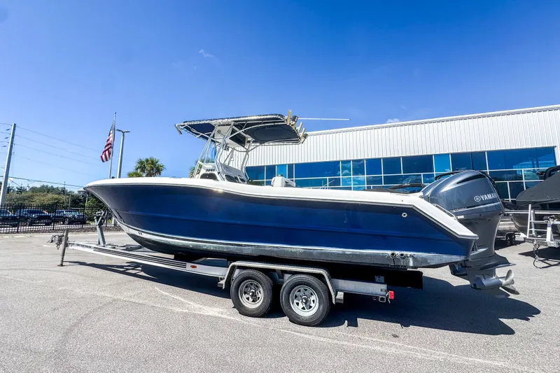 The Image of 2003 Triton 2895 CC boat on trailer, parked outdoors under clear blue sky. - 0