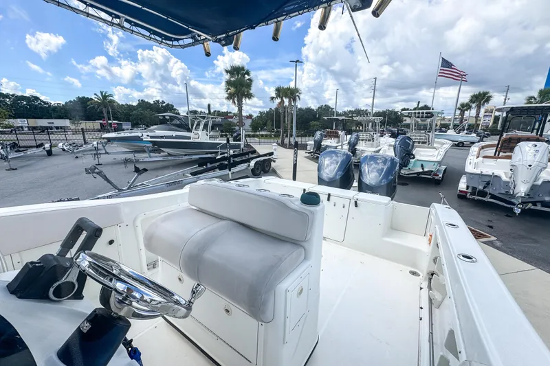 Slide: The Image of 2003 Triton 2895 CC boat interior with steering wheel, docked at marina under blue sky. - 10