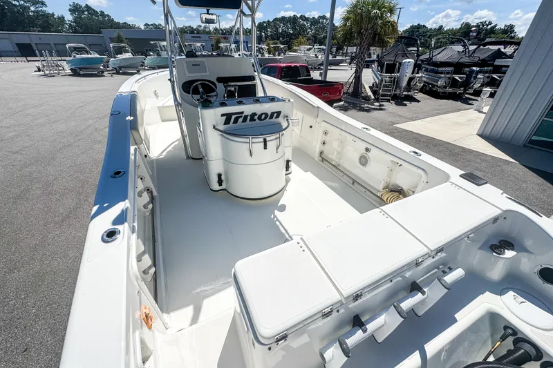 Slide: The Image of 2003 Triton 2895 CC boat interior with console and seating, parked outdoors. - 19