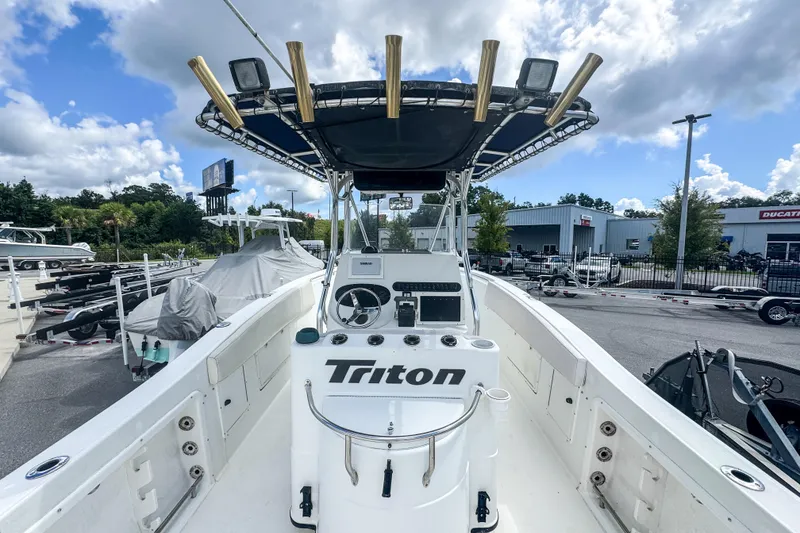 Slide: The Image of 2003 Triton 2895 CC boat with center console, docked under a partly cloudy sky. - 3