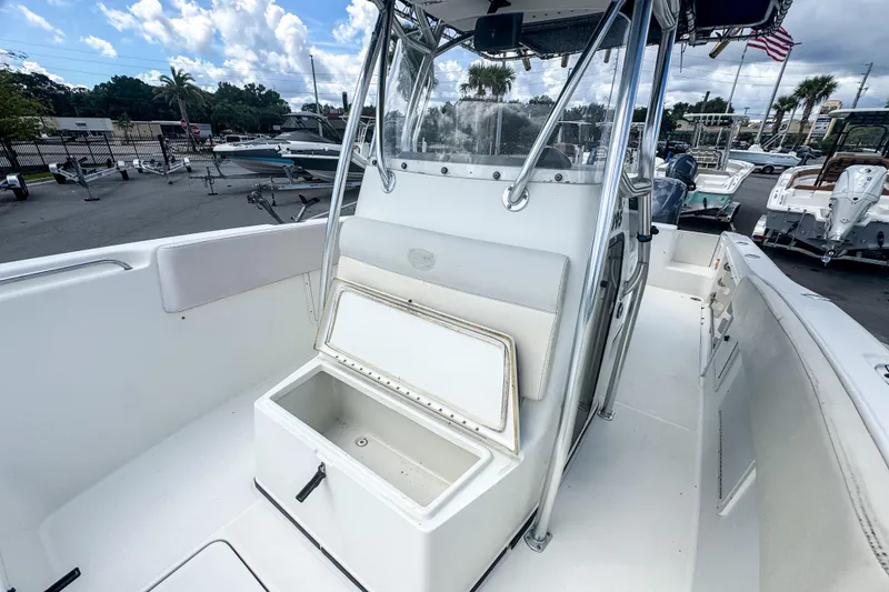 Slide: The Image of 2003 Triton 2895 CC boat with open storage compartment, docked under cloudy sky. - 8