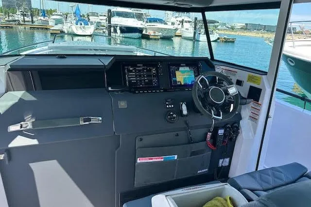 Slide: The Image of 2024 Axopar 37 XC Cross Cabin Wet Bar helm with modern navigation displays at marina. - 14