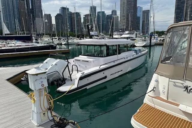 Slide: The Image of 2024 Axopar 37 XC Cross Cabin Wet Bar docked in a marina with city skyline. - 2