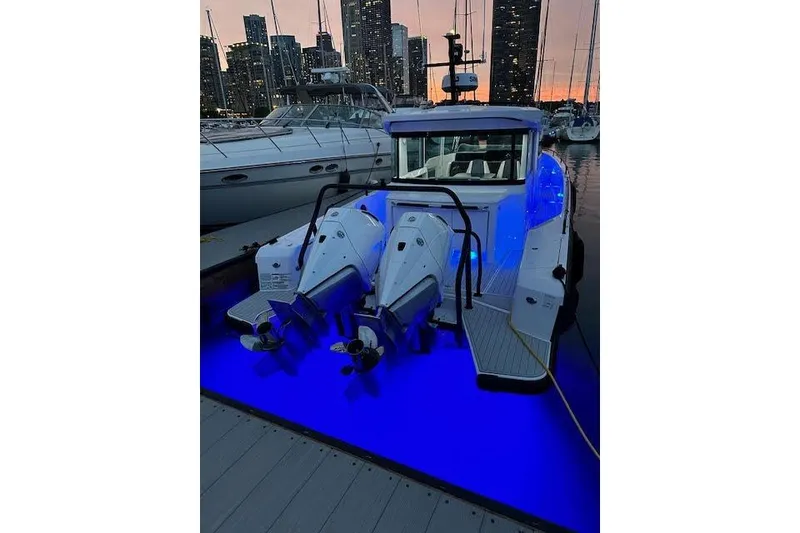 Slide: The Image of 2024 Axopar 37 XC Cross Cabin Wet Bar with illuminated blue deck at sunset. - 20