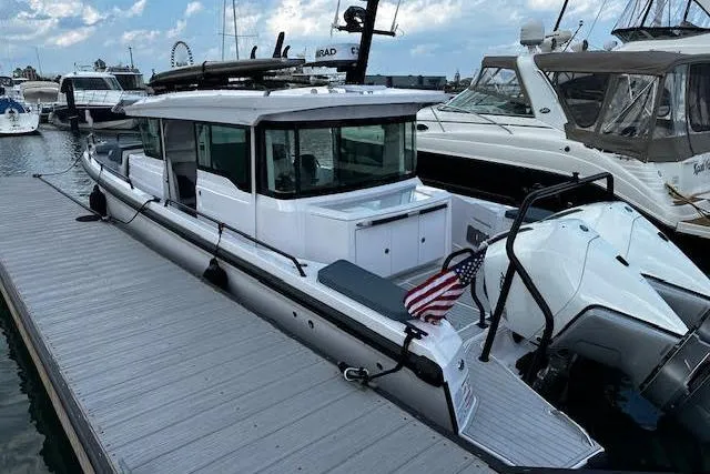 Slide: The Image of 2024 Axopar 37 XC Cross Cabin Wet Bar docked, featuring sleek design and American flag. - 5