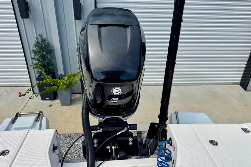 Slide: The Image of 2022 Robalo 266 Cayman boat engine at dockside with plants and metal siding. - 17