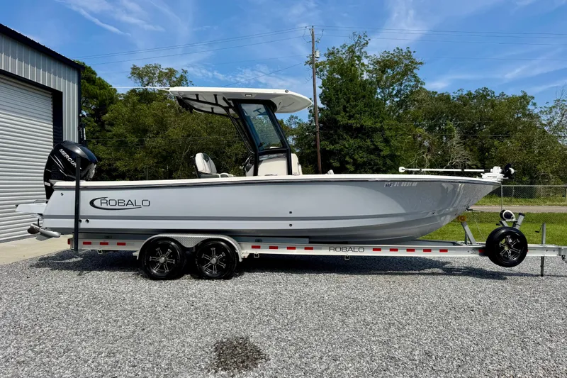 Slide: The Image of 2022 Robalo 266 Cayman boat on trailer, parked outdoors near a building. - 2